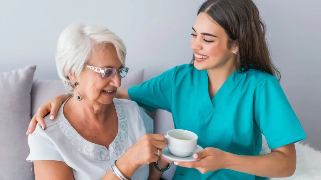 Enfermera entregando una taza con te a una abuelita